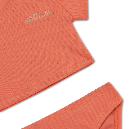 Coral-colored bikini with 'swim essentials' embroidery on a white background