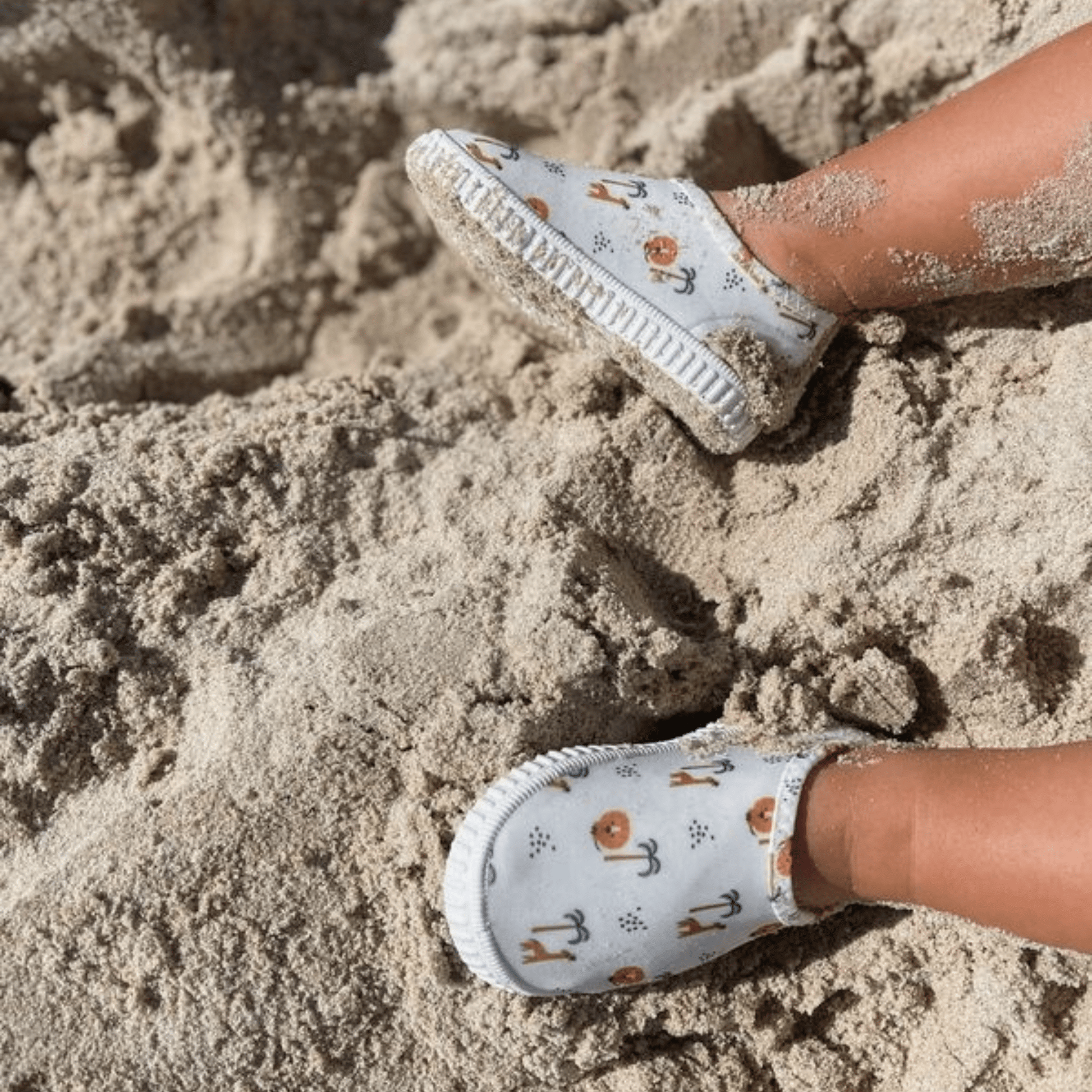 Children's water shoes with animal and jungle pattern on a sandy surface
