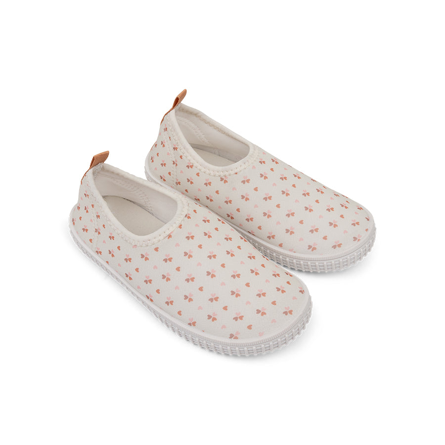 Pair of old pink water shoes with small cozy hearts pattern on a white background