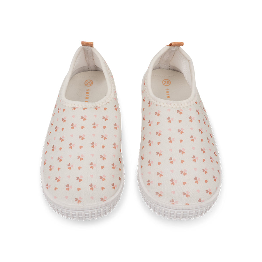 Pair of old pink water shoes with cozy hearts pattern on a white background