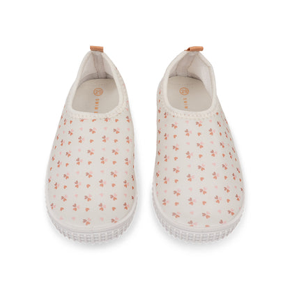 Pair of old pink water shoes with cozy hearts pattern on a white background