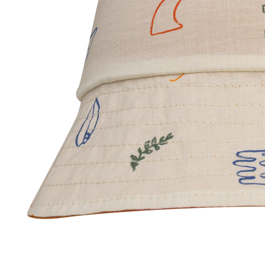 Close-up of a beige reversible hat with colorful sea designs on a white background