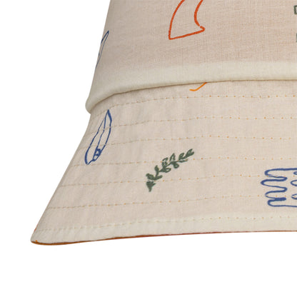 Close-up of a beige reversible hat with colorful sea designs on a white background