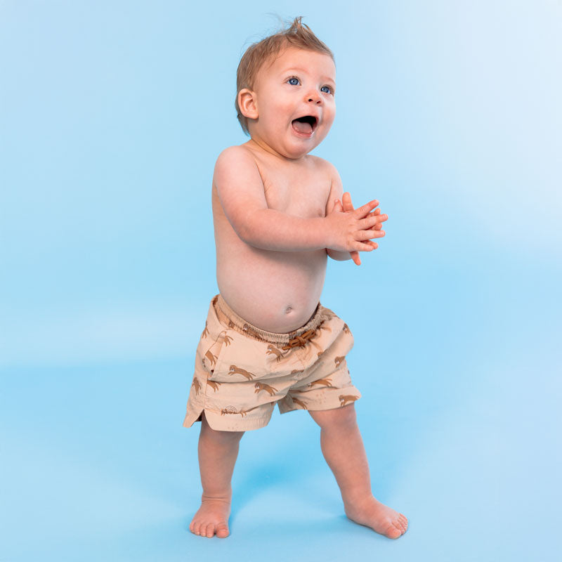 Baby wearing brown shorts with a pattern on a blue background