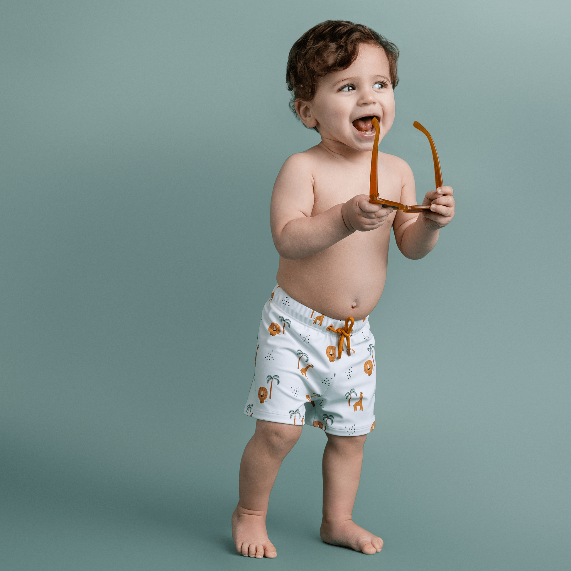 Child wearing light-colored shorts with animal prints against a plain background