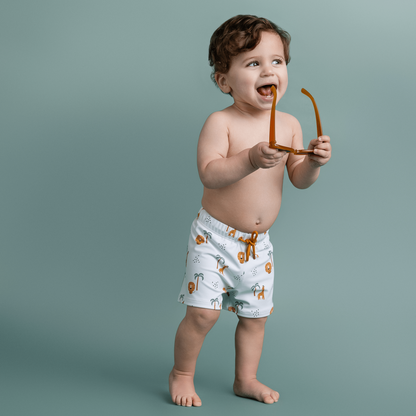 Child wearing light-colored shorts with animal prints against a plain background