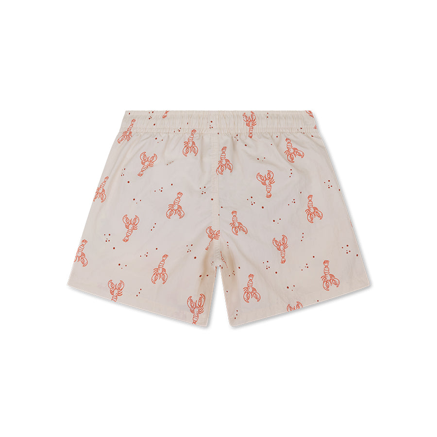 The back of beige swim shorts with red lobster pattern on a white background