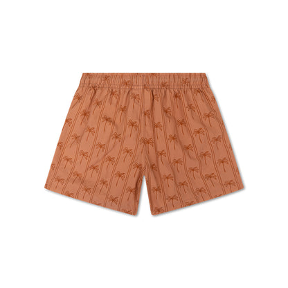 The back of brown swim shorts with palm tree pattern on a white background