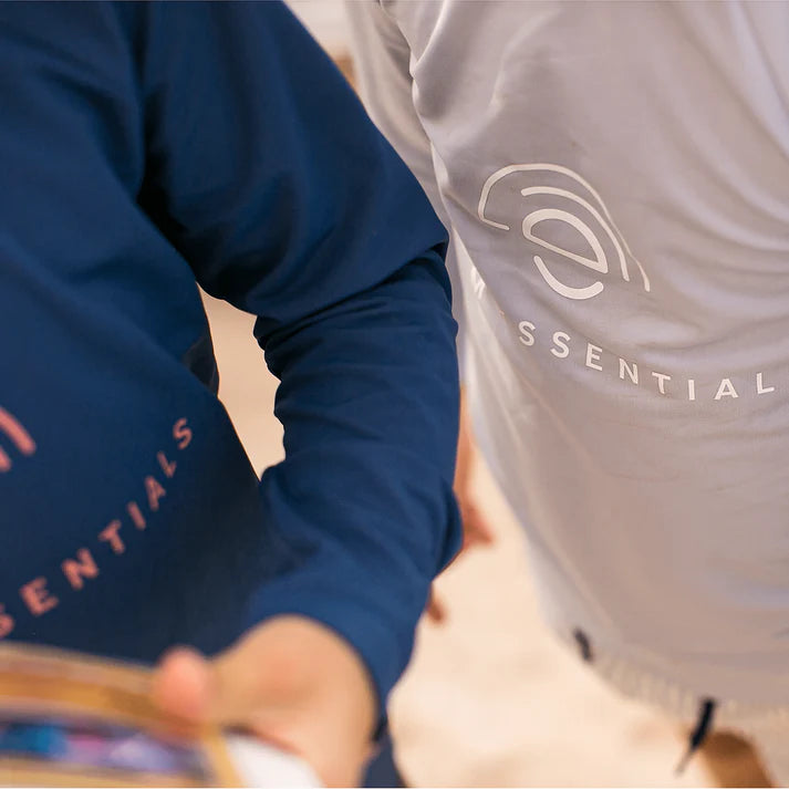 Two people wearing shirts with 'Swim Essentials' branding, one in blue and the other in gray.