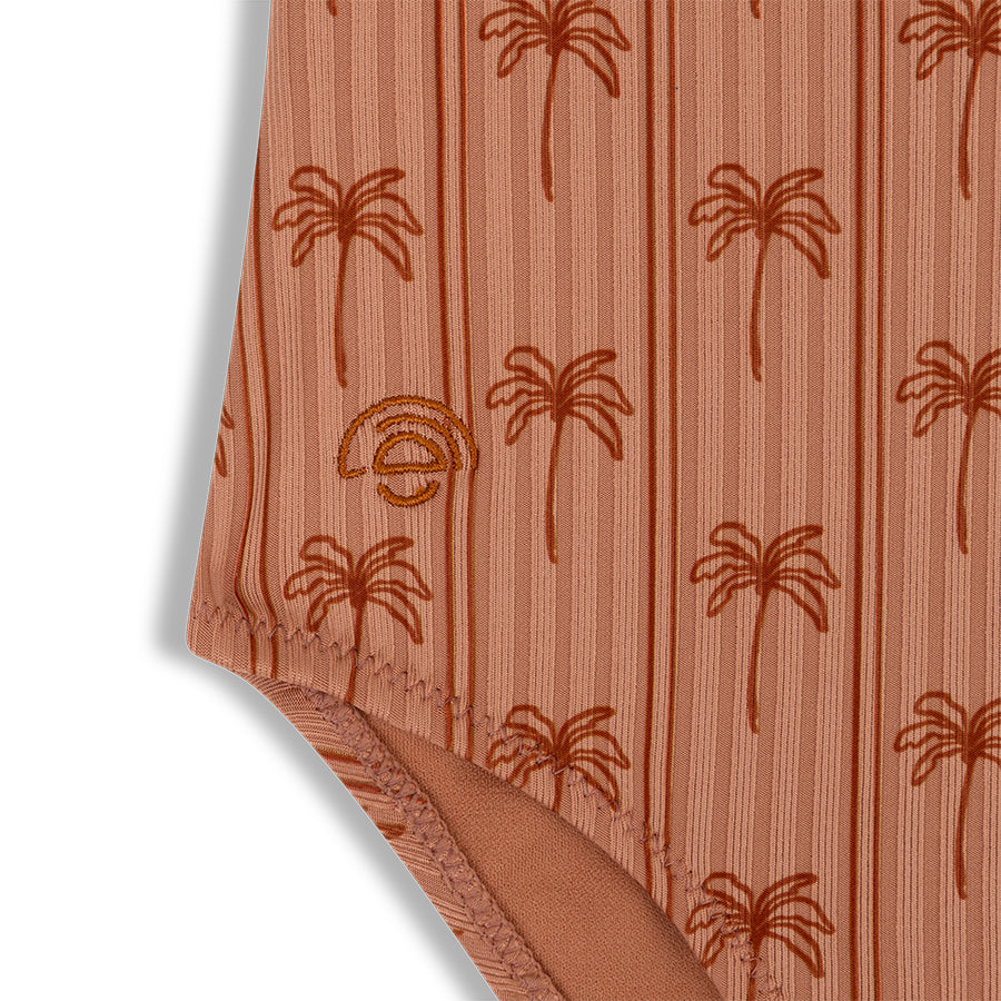 Close-up of a swimsuit with palm tree pattern on a white background