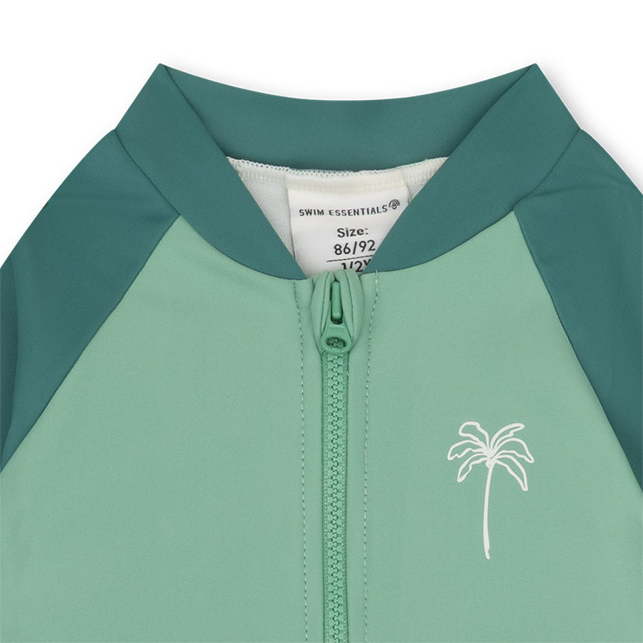 Green, dark green and whitechildren's swimsuit with palm tree design and size label.