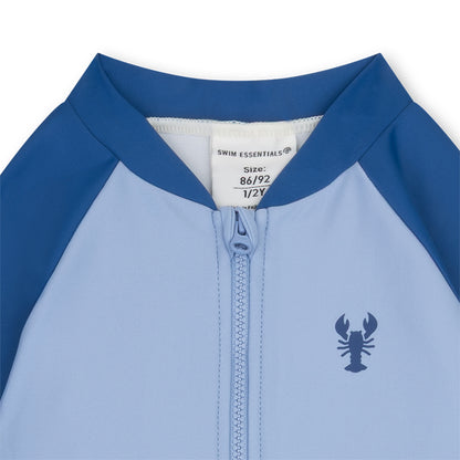 Close-up of a blue and light blue children's swimsuit with a lobster logo and brand label.