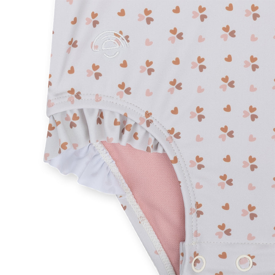 Detail of the swimsuit with heart pattern and pink lining on a white background