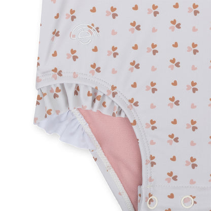 Detail of the swimsuit with heart pattern and pink lining on a white background