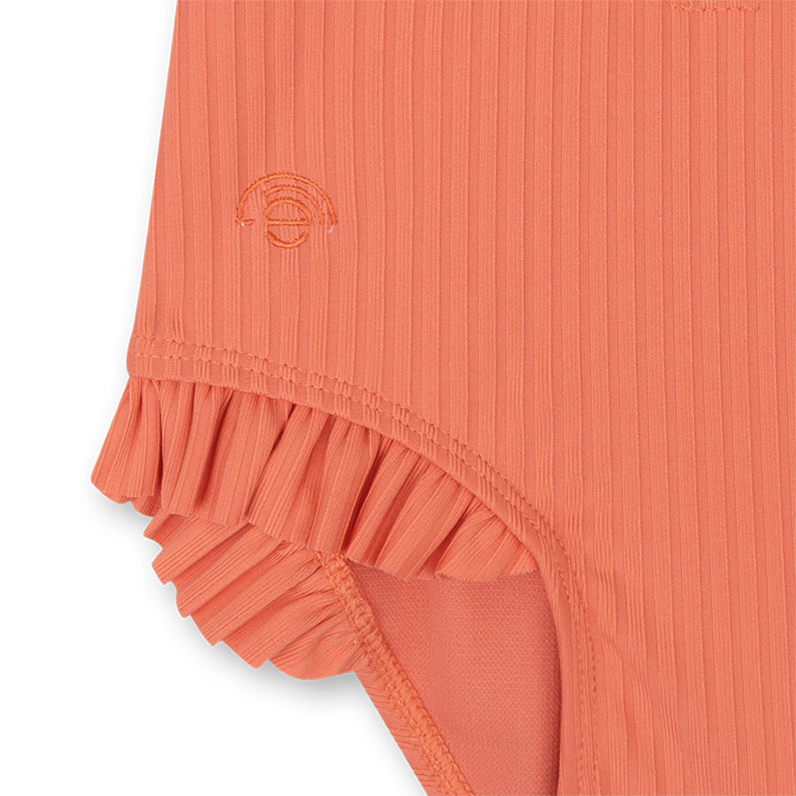 Close-up of a pink colored swimsuit with a subtle pattern on a white background
