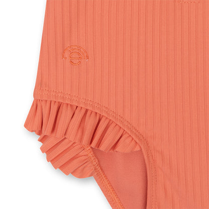 Close-up of a pink colored swimsuit with a subtle pattern on a white background
