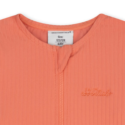 Close-up of a coral-colored garment with a brand logo and size label on a white background