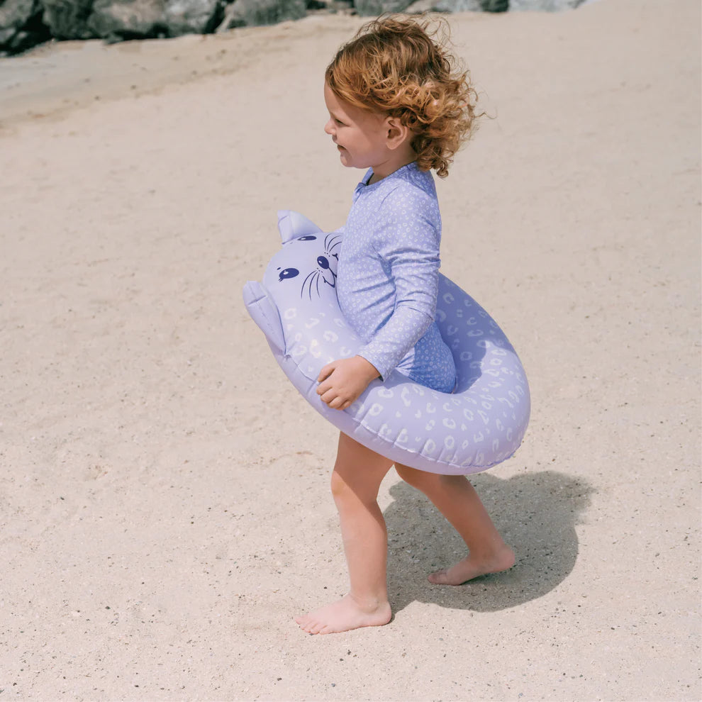 Child holding a purple inflatable ring on a sandy beach