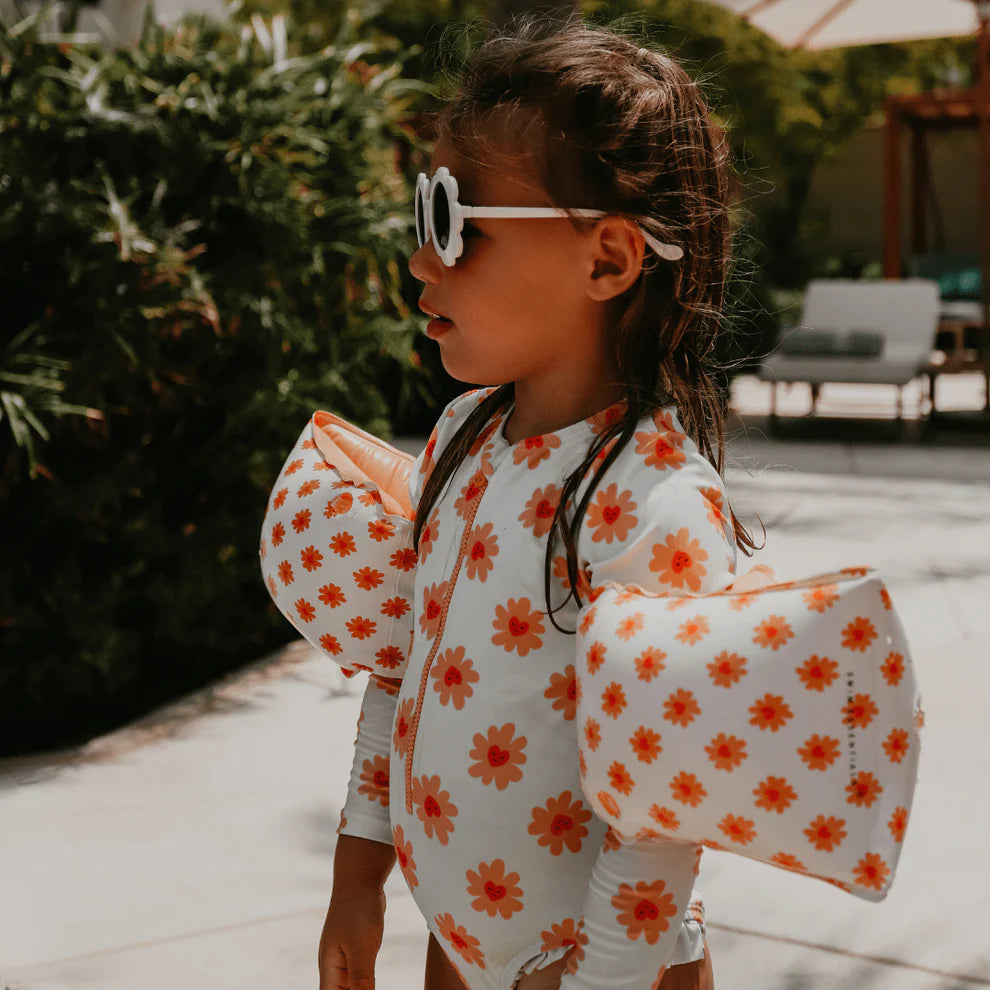 Child wearing a Floral Love swimsuit with arm bands outdoors