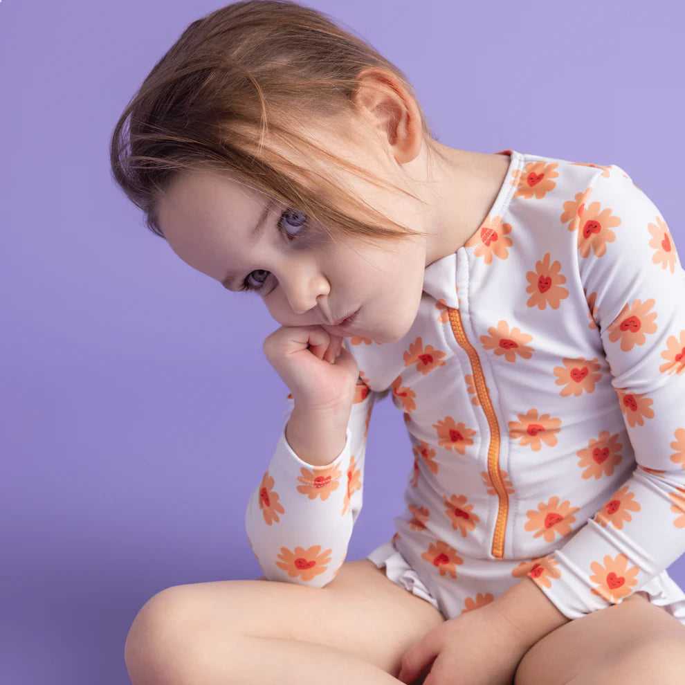 Child wearing a floral swimsuit with a purple background