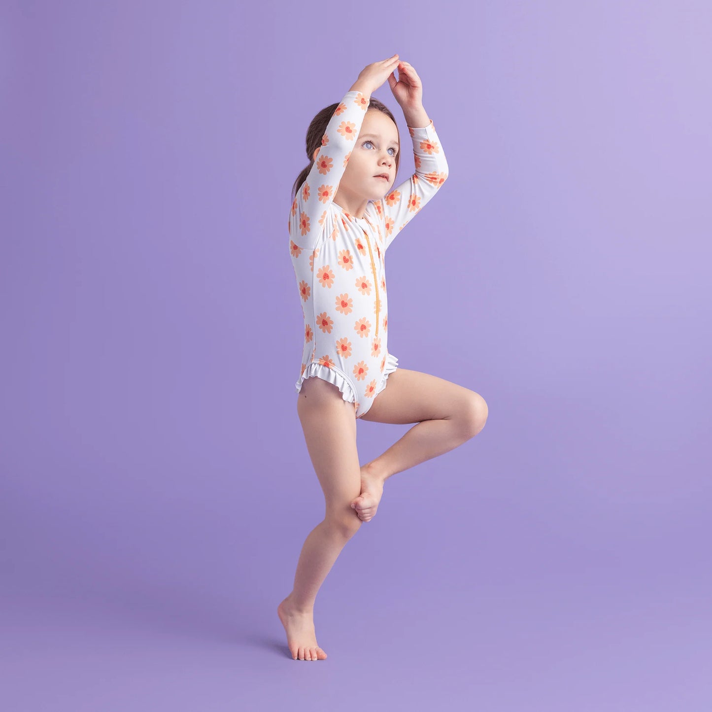 Young girl in a floral swimsuit posing in a purple background